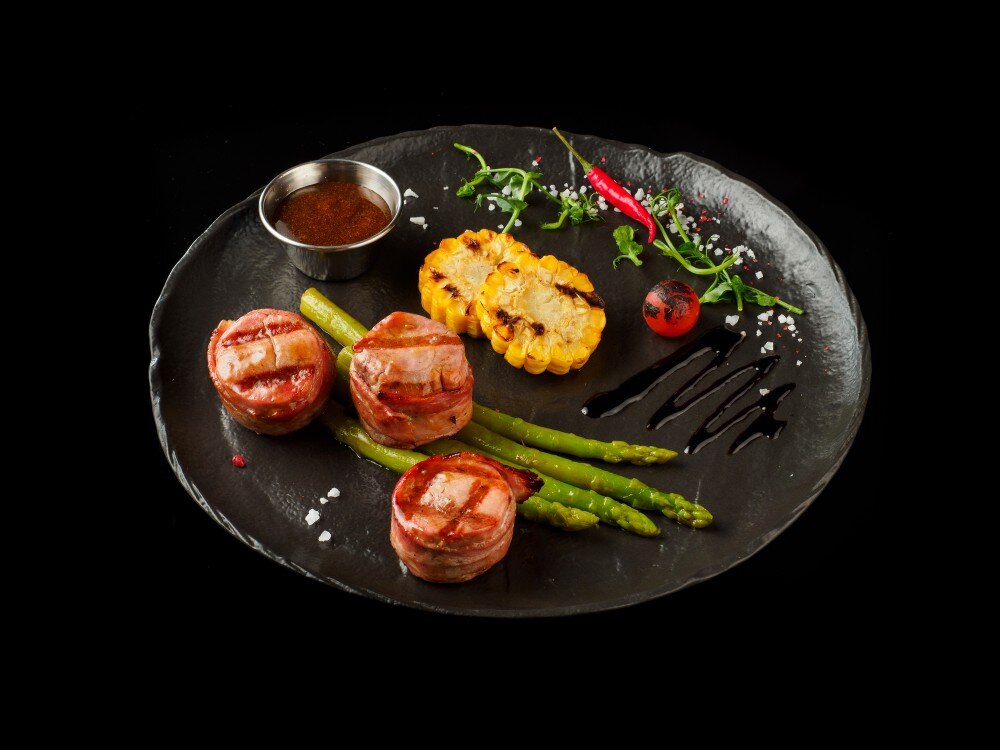 Медальоны из свинины в беконе с зелёной спаржей, кукурузой и соусом